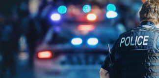 Police officer with patrol car and flashing lights.