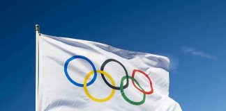 Olympic flag waving against clear blue sky