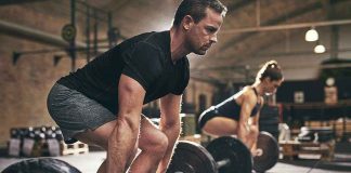 Man and woman lifting barbells in gym