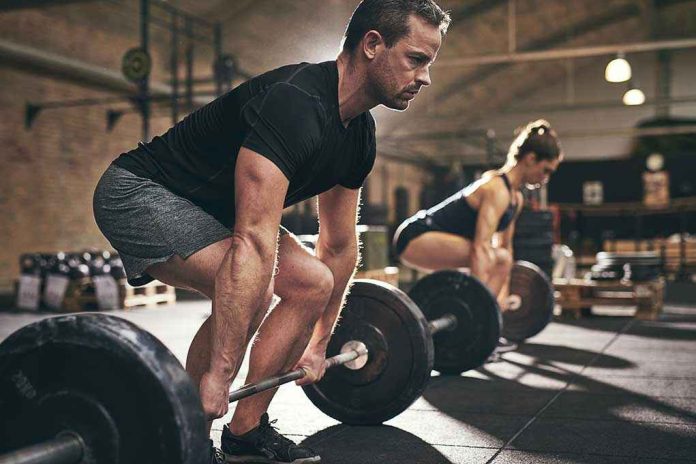 791792701 Man and woman lifting barbells in gym