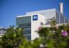 Modern hospital building with a prominent 'H' sign against a clear blue sky