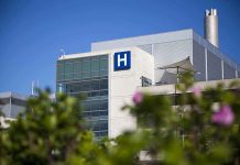 Modern hospital building with a prominent 'H' sign against a clear blue sky