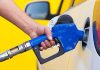 A person refueling a car at a gas station with a blue nozzle