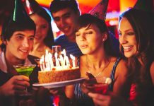 Group of friends celebrating a birthday with a cake and drinks