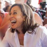 Woman laughing, surrounded by people with cameras.