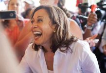 Woman laughing, surrounded by people with cameras.