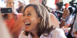 Woman laughing, surrounded by people with cameras.