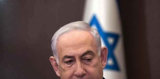 Man in suit with Israeli flag in background