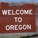 Welcome sign to Oregon with a brown background and white text