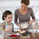 A mother and daughter baking together in a bright kitchen
