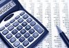 Calculator displaying BUDGET next to a financial spreadsheet and a pen