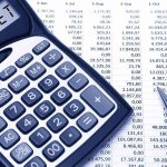Calculator displaying BUDGET next to a financial spreadsheet and a pen