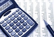 Calculator displaying BUDGET next to a financial spreadsheet and a pen