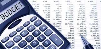 Calculator displaying BUDGET next to a financial spreadsheet and a pen