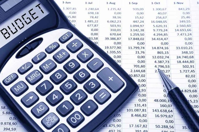 Calculator displaying BUDGET next to a financial spreadsheet and a pen
