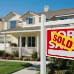 A house with a Sold sign in the front yard