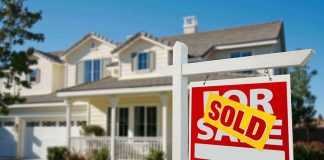 A house with a Sold sign in the front yard