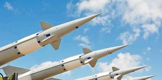 Multiple missiles pointed upward on launchers against blue sky