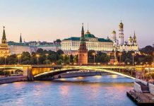 Illuminated bridge and Kremlin complex across river at twilight
