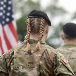 Troop Pay Shock: Trump Bypasses Congress Soldier with braided hair in uniform American flag visible