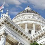Capitol building dome and flags under a blue sky