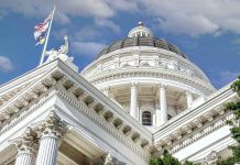 Capitol building dome and flags under a blue sky