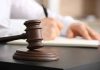 Judges gavel on desk with person writing