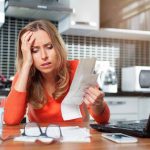 One Call DESTROYS Inflated Service Bills Woman looking stressed holding bills in kitchen