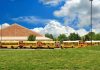 Waymo Robotaxi Ignores LAW—Regulators Stunned A row of yellow school buses parked in front of a school building under a cloudy sky