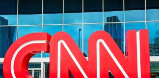 Large red CNN logo in front of a glass building