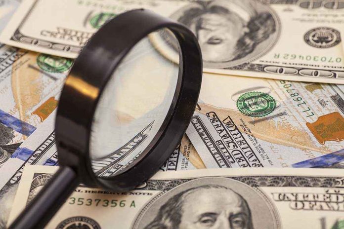 shutterstock_221003320.jpg A magnifying glass resting on a pile of US dollar bills