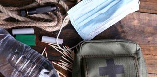 An assortment of emergency supplies including a first aid kit water bottle face mask and matches