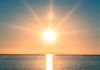 A serene sunrise over a calm ocean with vibrant colors in the sky