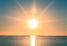 A serene sunrise over a calm ocean with vibrant colors in the sky