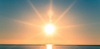 A serene sunrise over a calm ocean with vibrant colors in the sky