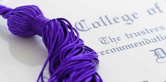 Close up of a purple graduation tassel next to a diploma