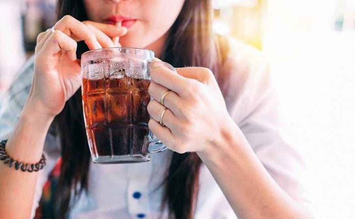 1033381774 Person drinking soda from a glass mug