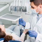 Oral Health SABOTAGE: Are You at Risk?! Dentist examining a patient in a dental chair.