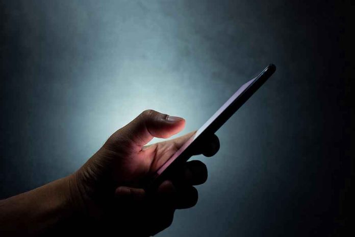 Hand holding a smartphone in the dark.