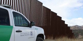 Border protection vehicle near a large metal fence