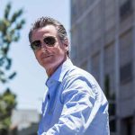 Newsom’s Grid Gamble Sparks Military Panic Man in sunglasses wearing a blue button-up shirt.