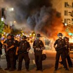 Chaos Erupts: Feds Unleash Force on Portland Police officers in riot gear near burning car.