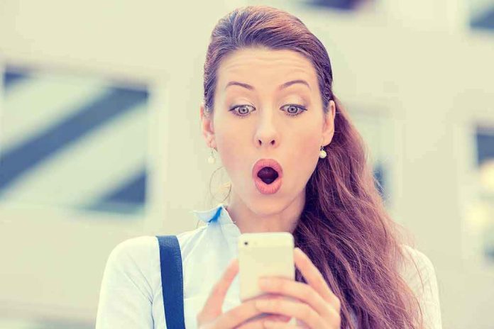 237618796 Surprised woman looking at her smartphone outdoors