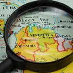 Trump’s Bold Move: Venezuela’s Drug War Heats Up Magnifying glass focusing on Venezuela and Colombia on map