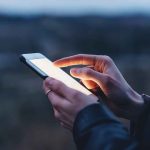 Ben Shapiro – Candace Owens Feud is UGLY Person using a smartphone at dusk.