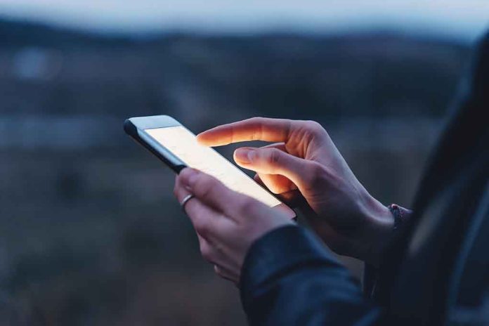 585973055 Person using a smartphone at dusk.