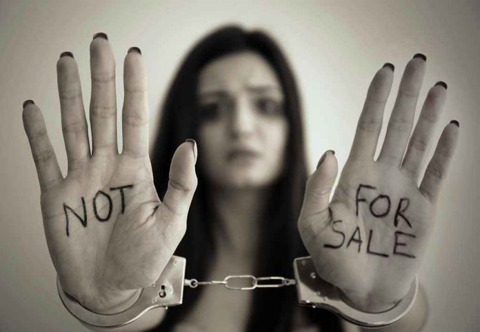 631031339 Handcuffed woman shows NOT FOR SALE on her palms.