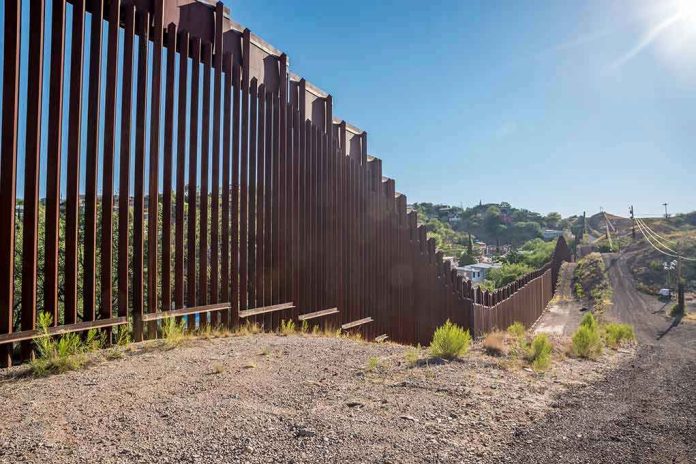 Tall metal border wall with rural landscape