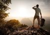 Hiker standing on a rocky outcrop overlooking a valley at sunset