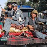 Biden’s Afghan Disaster Gets WORSE Three armed soldiers sitting on the back of a military vehicle in an urban setting